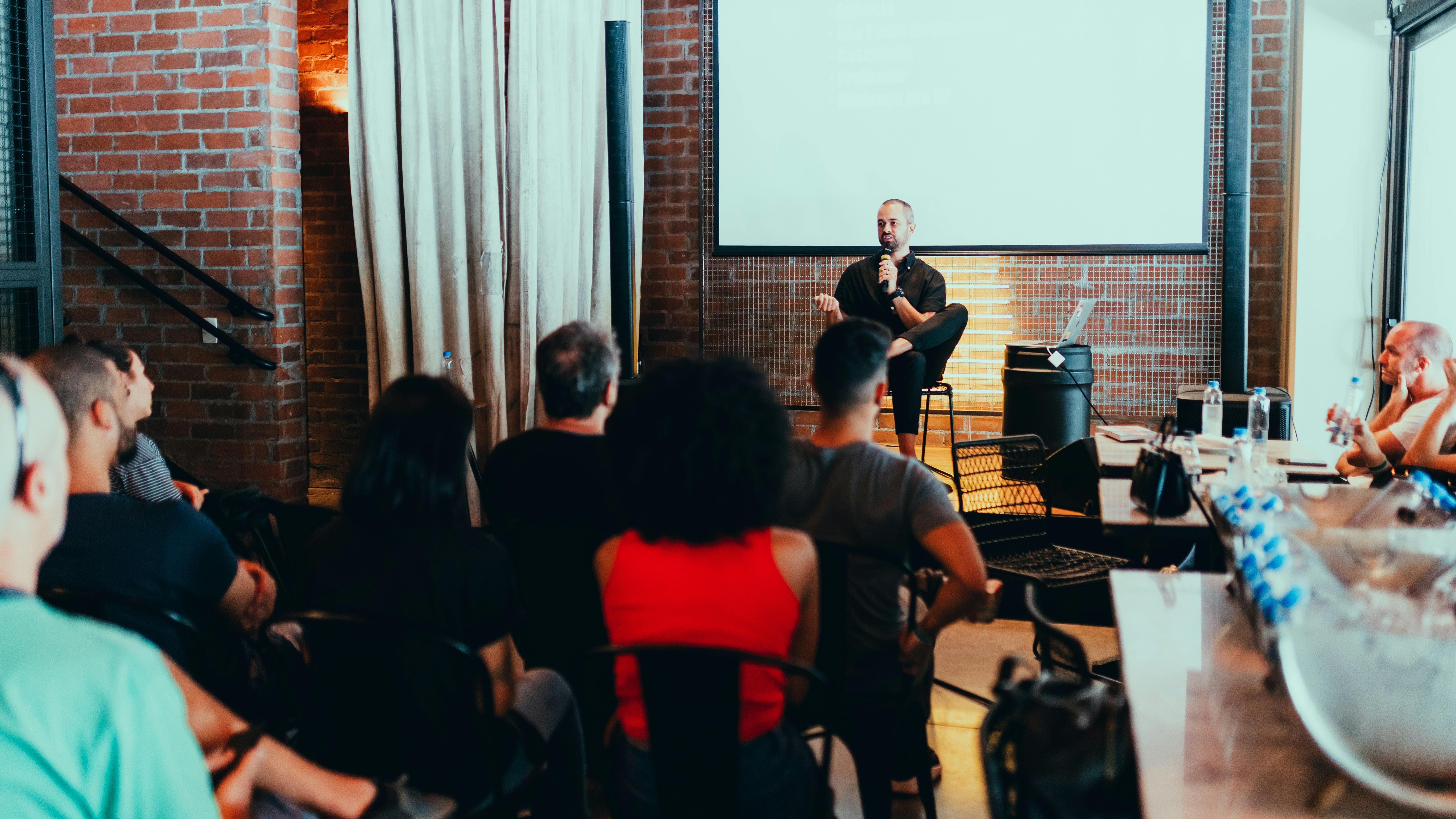Personnes assises dans une salle pendant une conférence avec un animateur.